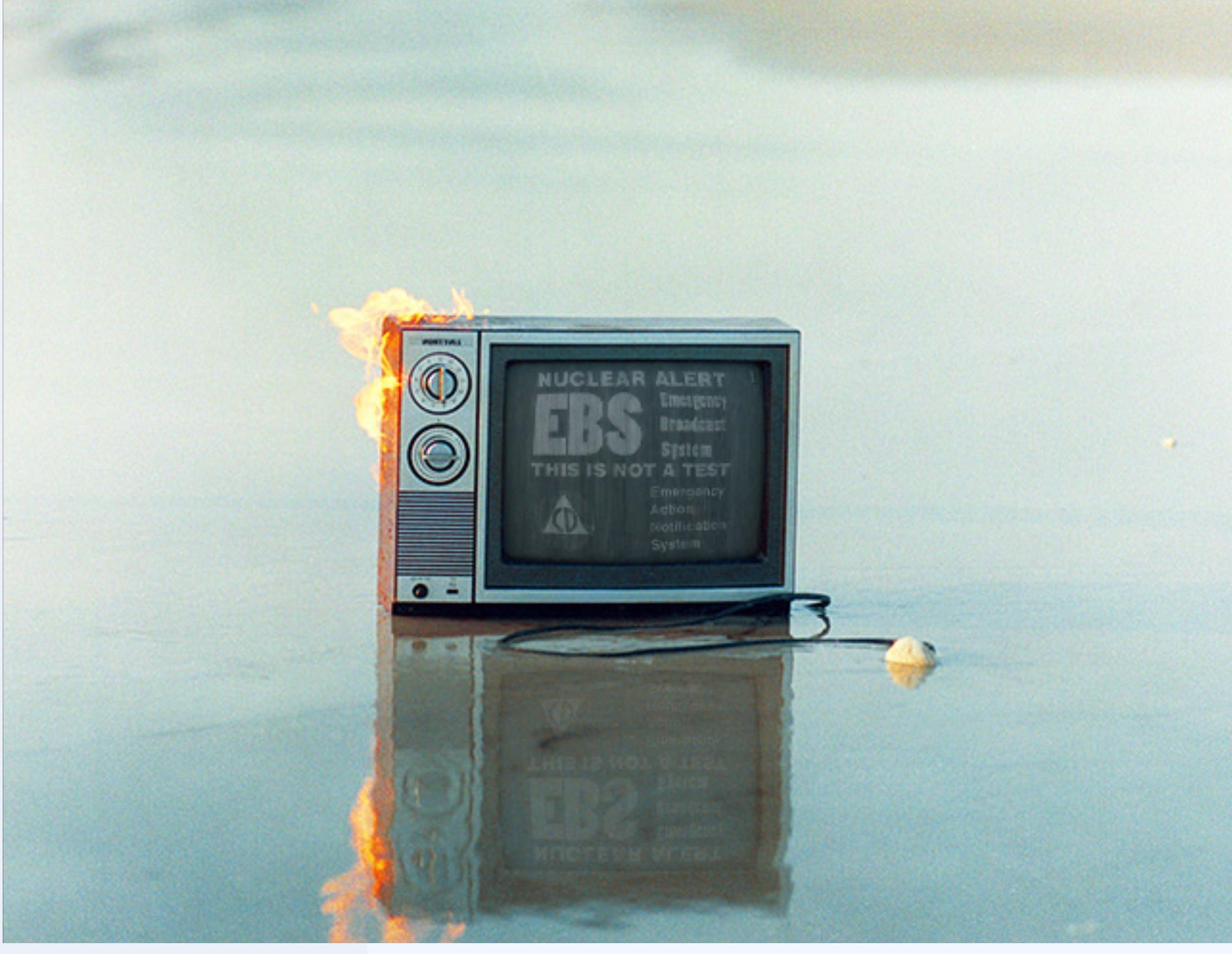 Surreal illustration of a burning television floating on water, nuclear alert screen