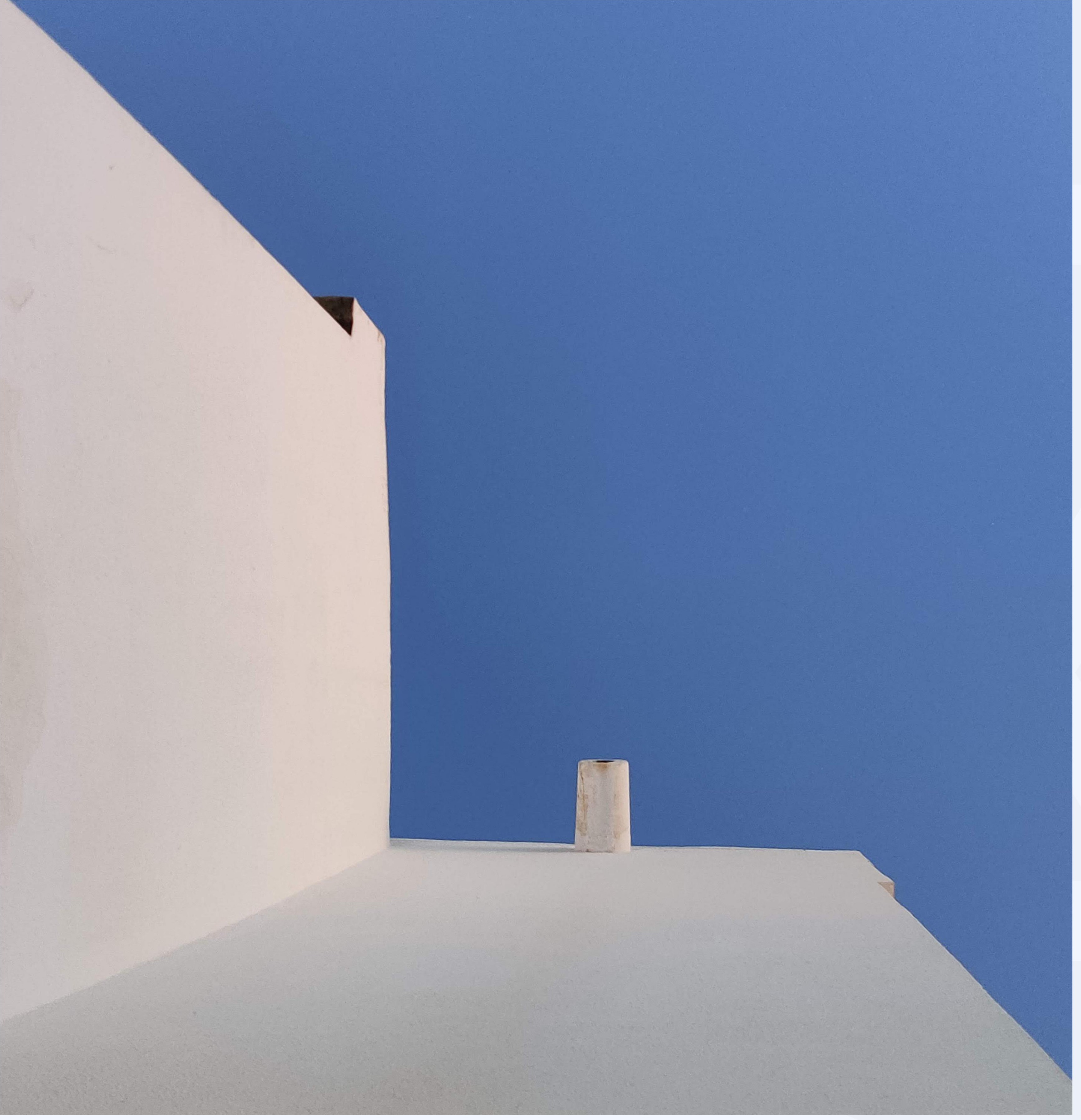 Looking up at a white building corner against a blue sky
