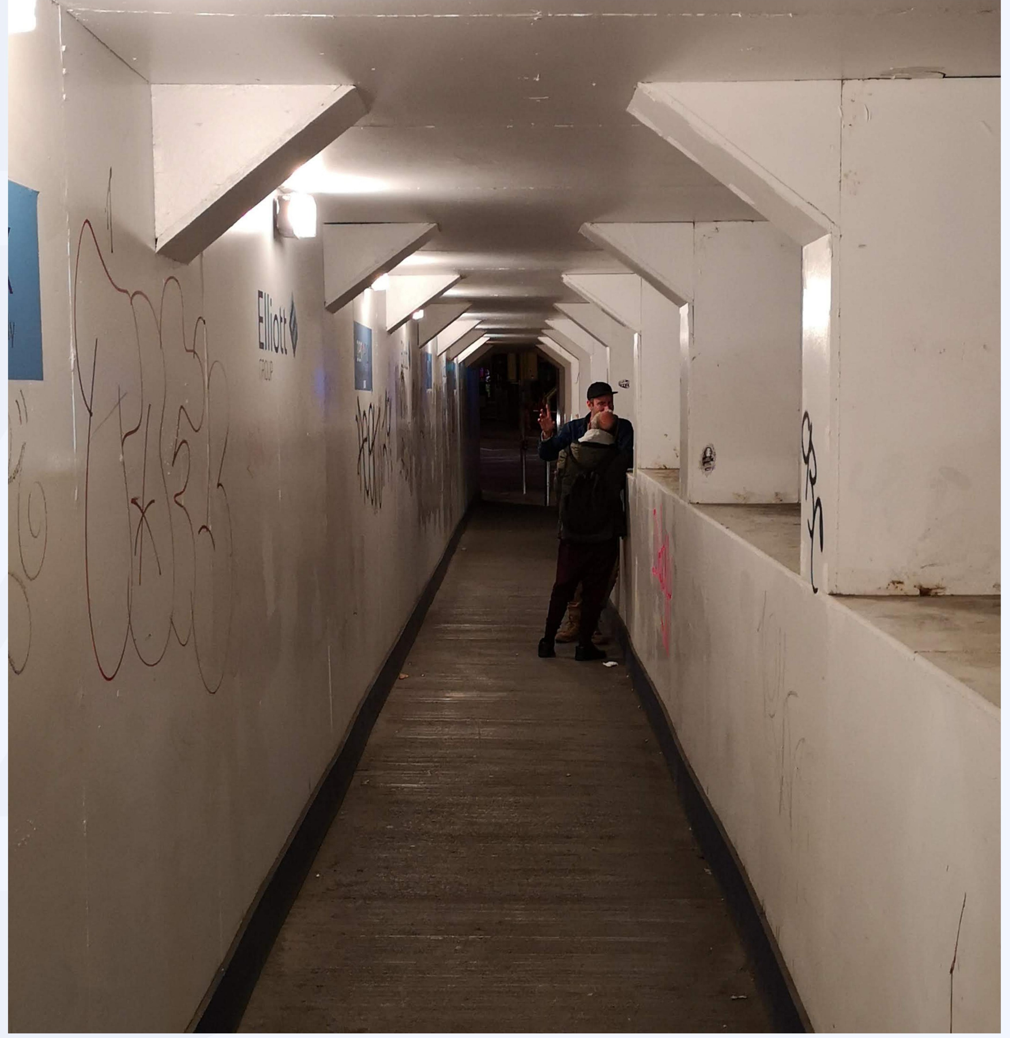 Graffitied pedestrian tunnel with a figure walking through