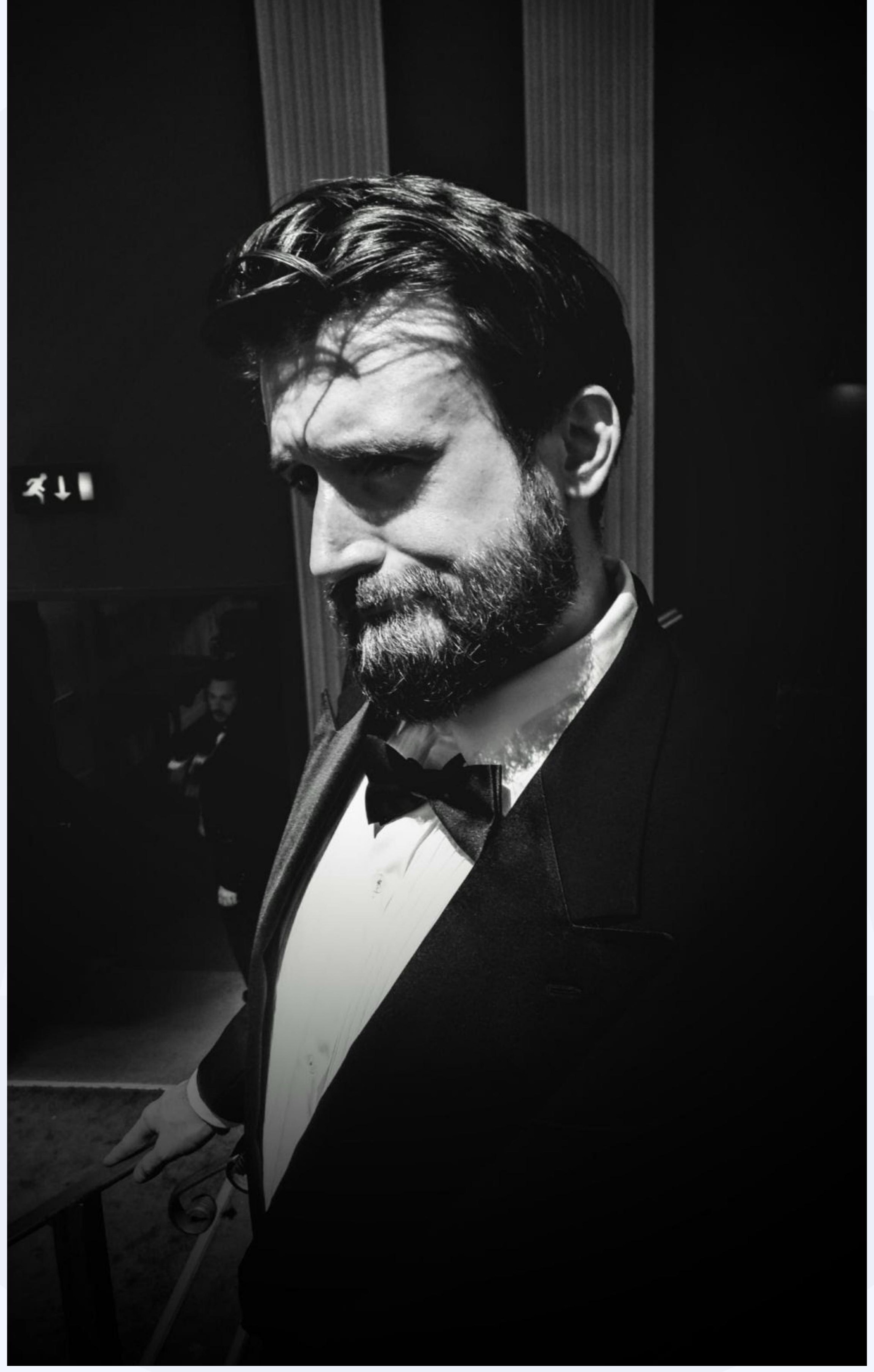 Black and white portrait of a bearded man in a tuxedo